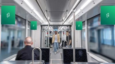 Vue intérieure d’un véhicule des transports publics avec plusieurs espaces publicitaires dans la rame; des voyageurs flous apparaissent à l’arrière-plan.