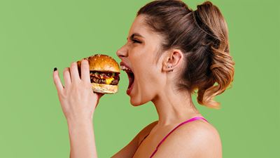 Junge Frau beisst mit Vorfreude in einen saftigen Burger