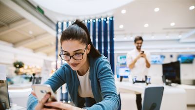 Eine potentielle Käuferin in einem Laden benutzt ein Smartphone