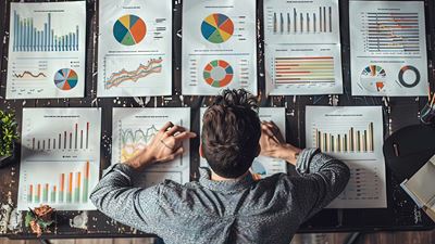 Angestellter überprüft Statistiken und Diagramme, um Key Performance Indicators (KPI) nachzuverfolgen