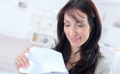 Eine Frau öffnet ein Mailing und lächelt dabei